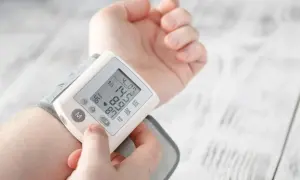 Dłoń z założonym ciśnieniomierzem nadgarstkowym pokazującym wynik 145/87 mmHg i puls 46/min.