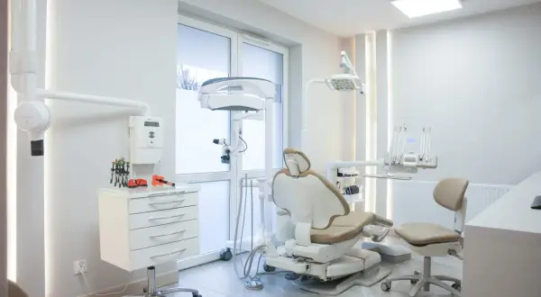 Nowoczesny gabinet stomatologiczny z fotelem dentystycznym i sprzętem.