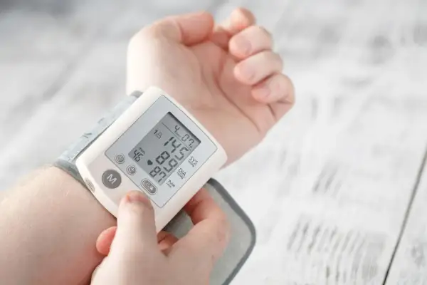 Dłoń z założonym ciśnieniomierzem nadgarstkowym pokazującym wynik 145/87 mmHg i puls 46/min.
