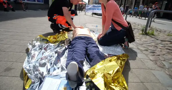 Ćwiczenia pierwszej pomocy: pozycja czterokończynowa przy omdleniu na kocu termoizolacyjnym.